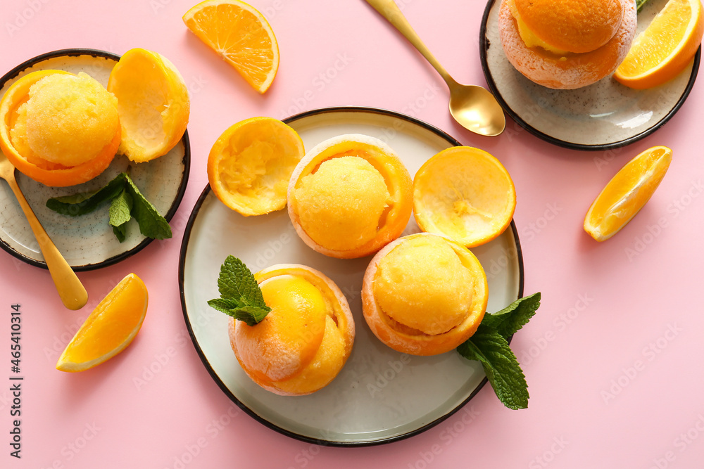 Plates with tasty ice creams in orange peels on color background