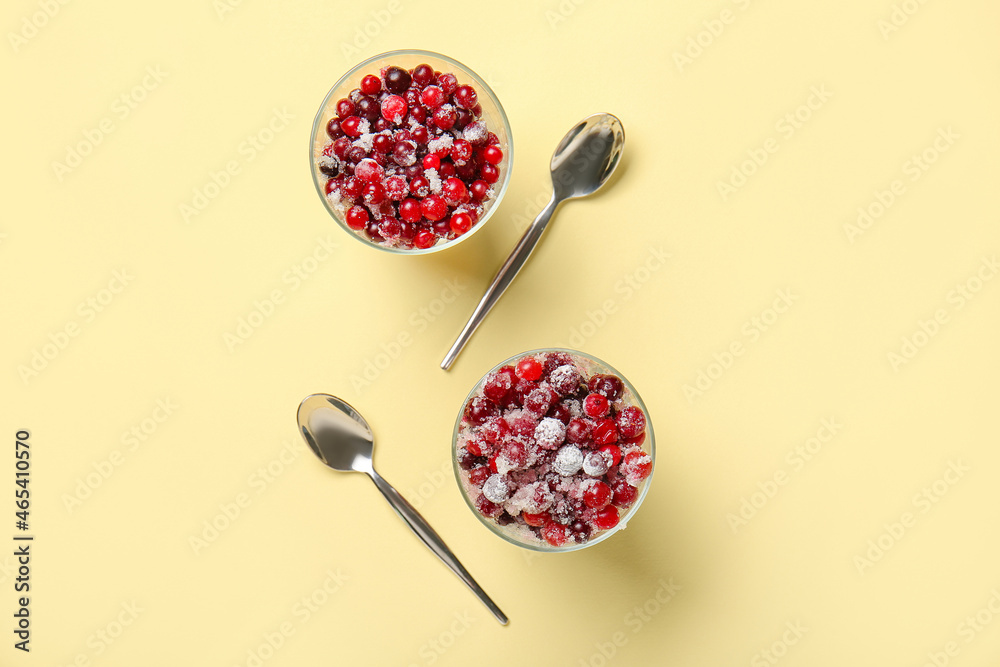 Glass bowls with tasty sugared cranberries on beige background