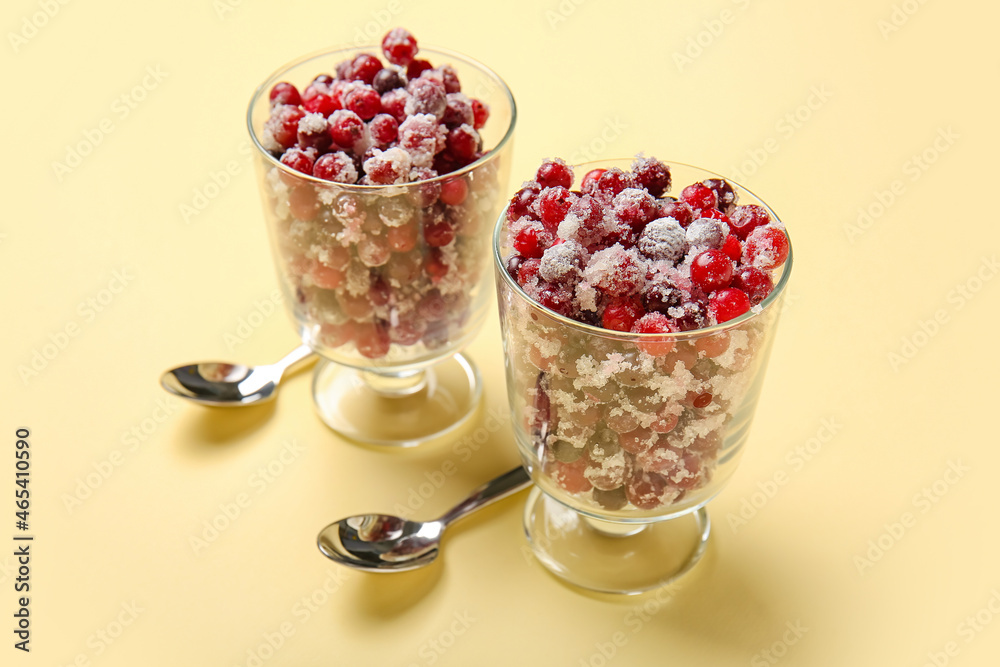 Glass bowls with tasty sugared cranberries on beige background