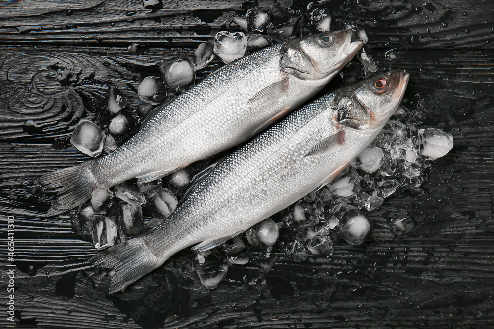 Fresh uncooked sea bass fish on black wooden background