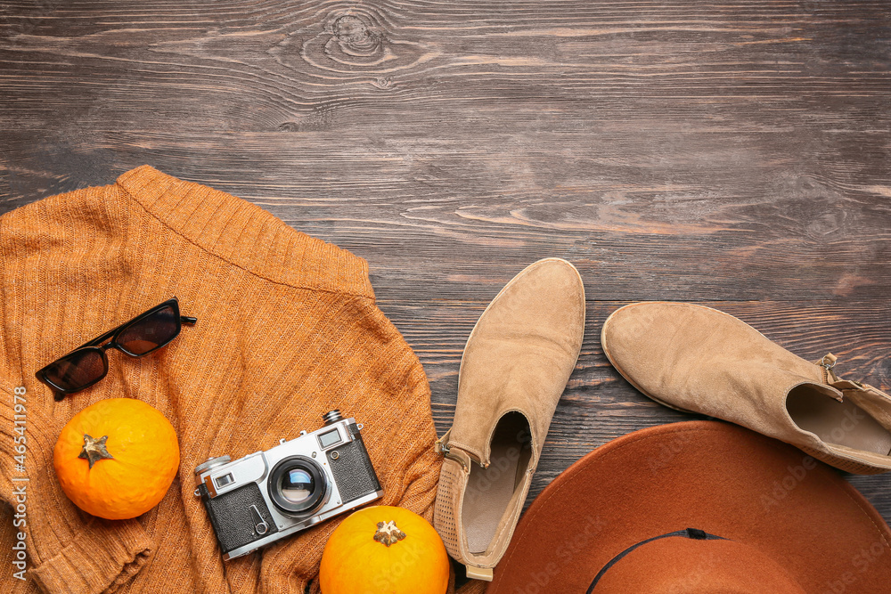 Female clothes, photo camera and pumpkins on wooden background