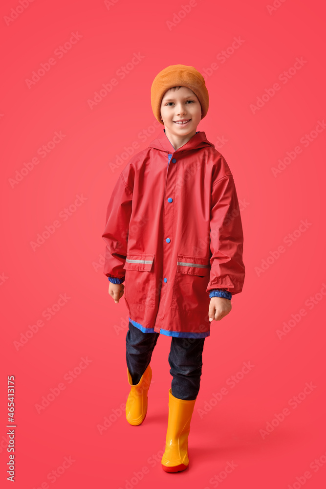 Little boy in raincoat on color background