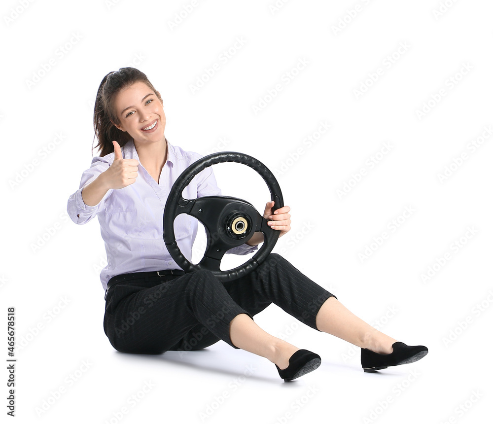 Young businesswoman with steering wheel showing thumb-up on white background