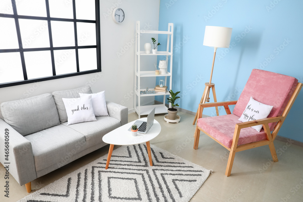 Interior of stylish room with comfortable armchair and sofa near color wall