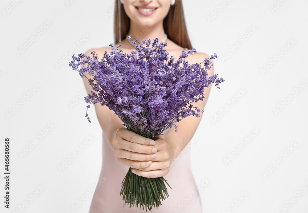 美丽的年轻女子，浅色背景上有一束薰衣草