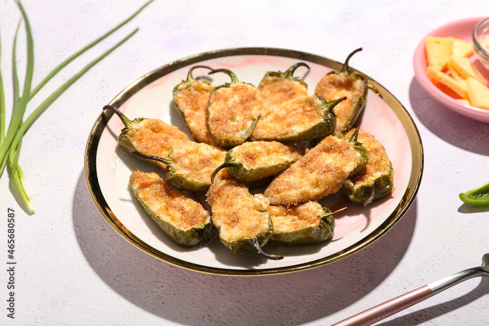 Plate with delicious jalapeno poppers on light background