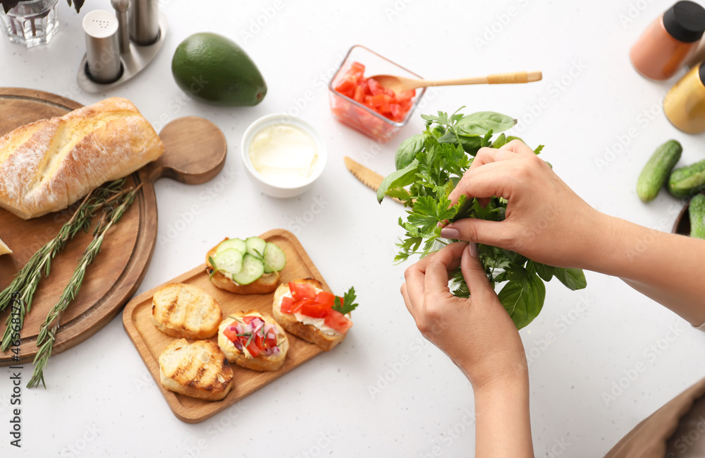 Woman cooking tasty vegetarian bruschettas at table in kitchen