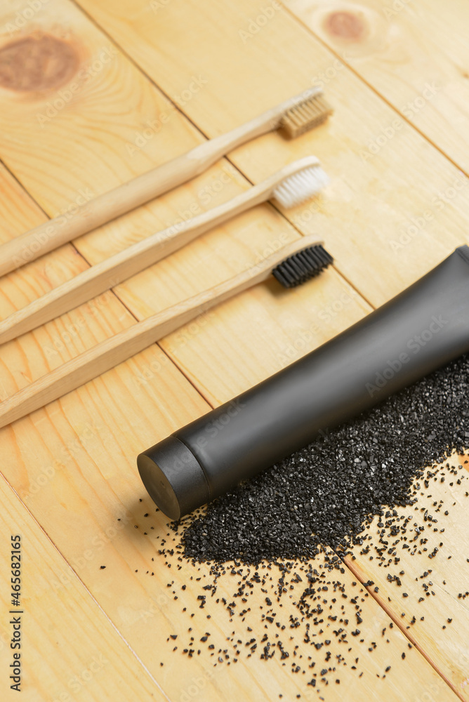 Black toothpaste with activated carbon and brushes on wooden background