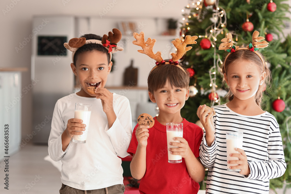 Little children with cookies and glasses of milk at home on Christmas eve