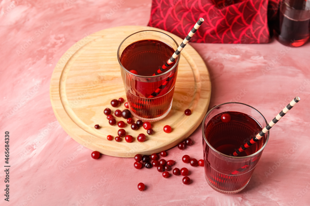 Glasses with tasty cranberry juice on color background