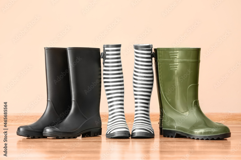 Many different rubber boots near color wall