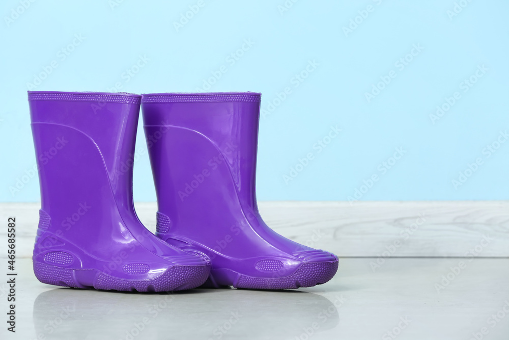 Rubber rain boots against color wall