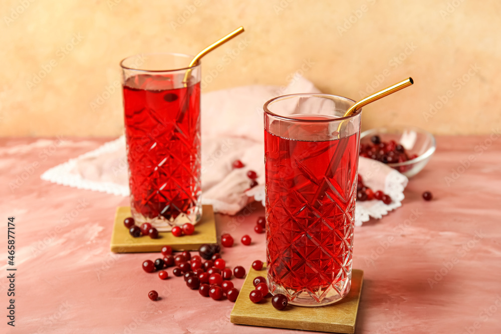 Glasses with tasty cranberry juice on color background