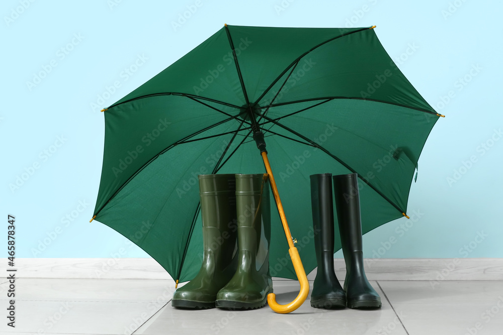 Gumboots and umbrella against color wall