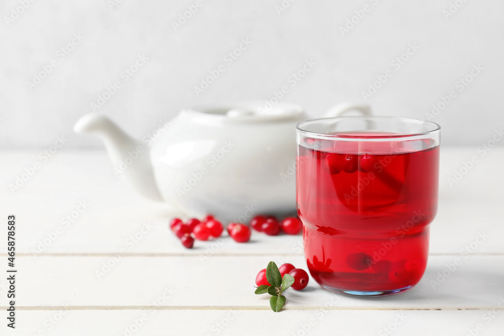 Glass of tasty lingonberry tea on table