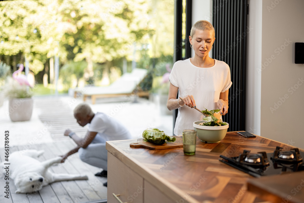 Black man caress dog while his european girlfriend looking on it and holding bowl with salad. Concep