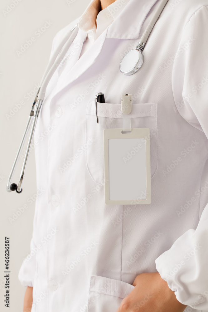 close up of a doctors clean uniform with stethoscope, pen and ID card.