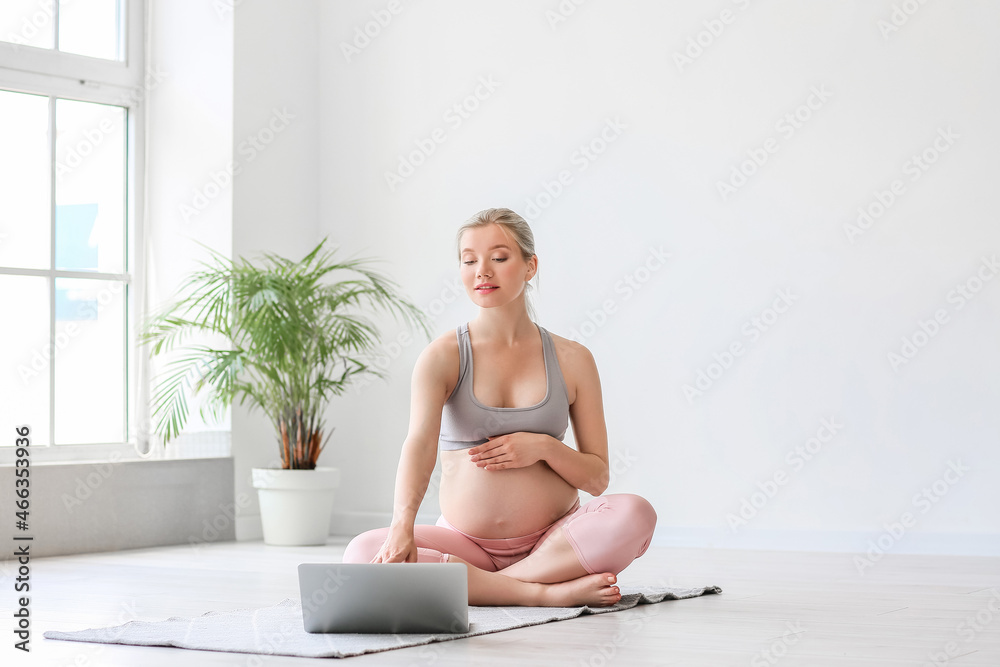 Sporty pregnant woman using laptop indoors