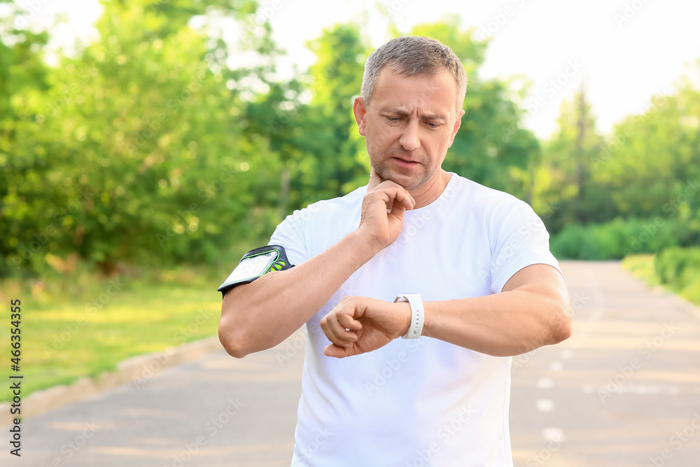 Male runner checking pulse outdoors