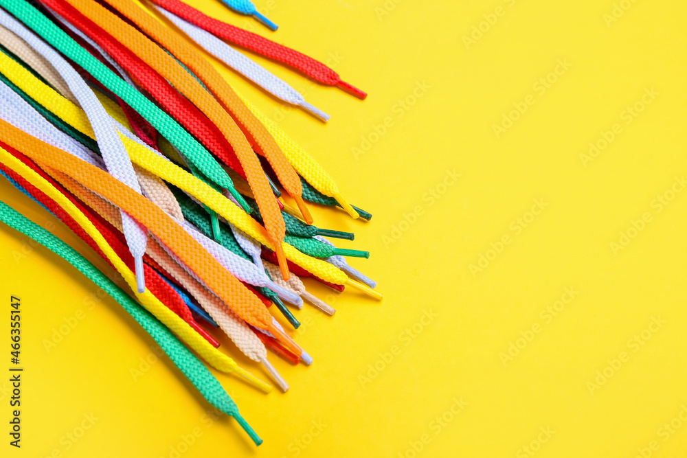 Many different shoe laces on yellow background, closeup