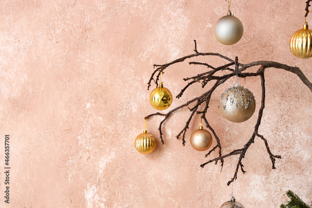 Tree branches with Christmas balls near pink wall, closeup