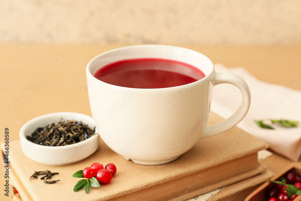 Cup of tasty lingonberry tea and books on table