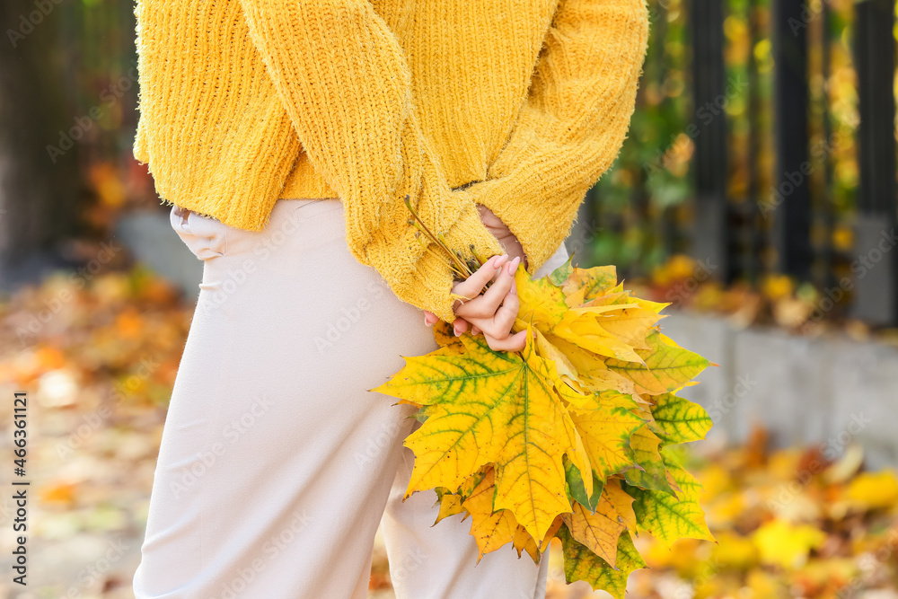 Young woman holding autumn bouquet behind her back, closeup