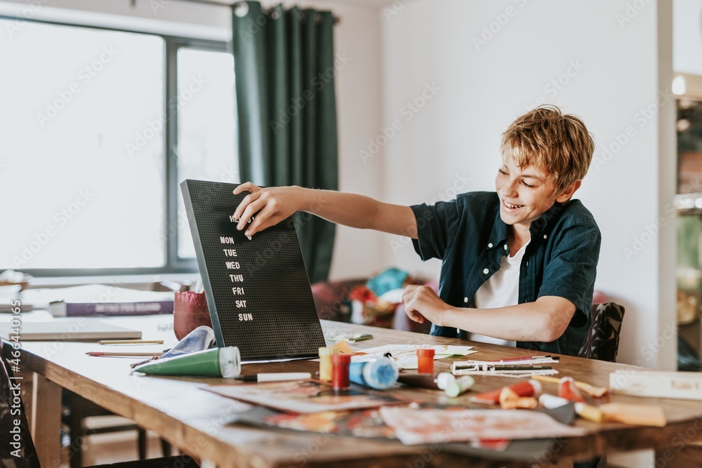 Boy creating text on black letter board