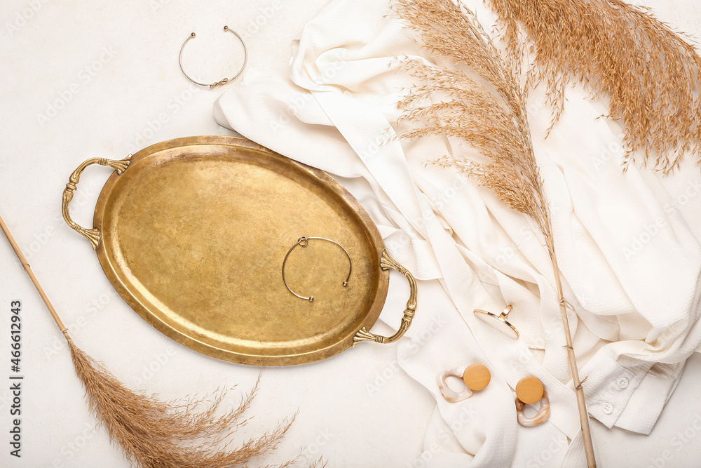 Dry reeds, golden tray and stylish female accessories on light background