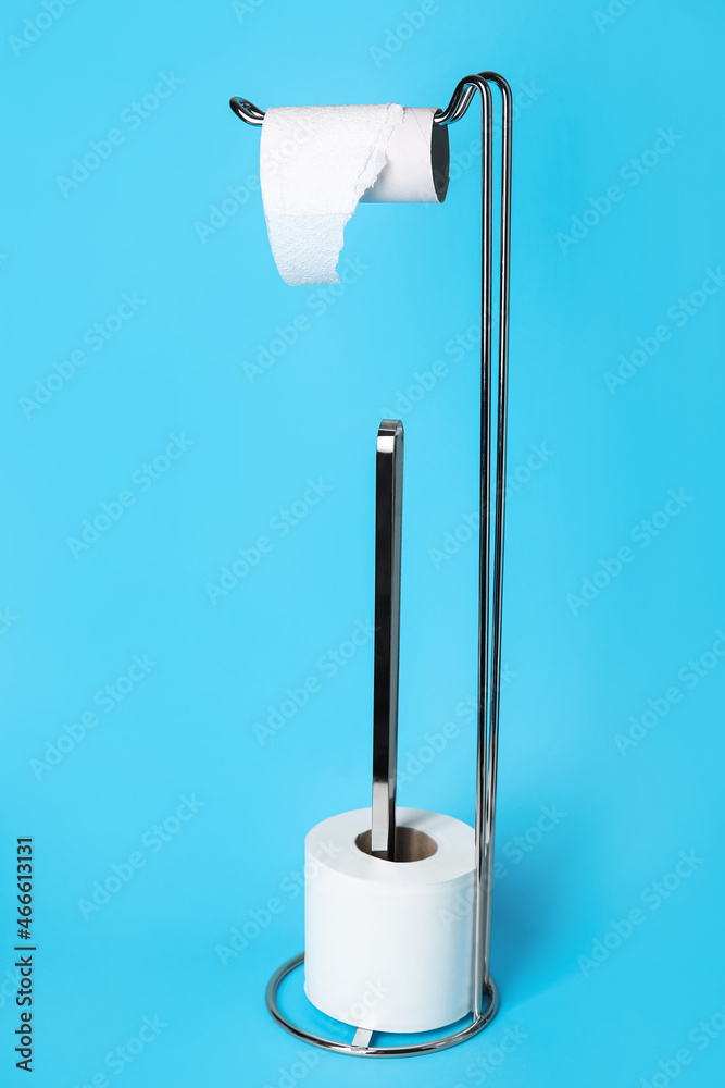 Modern holder with cardboard tube and toilet paper roll on blue background