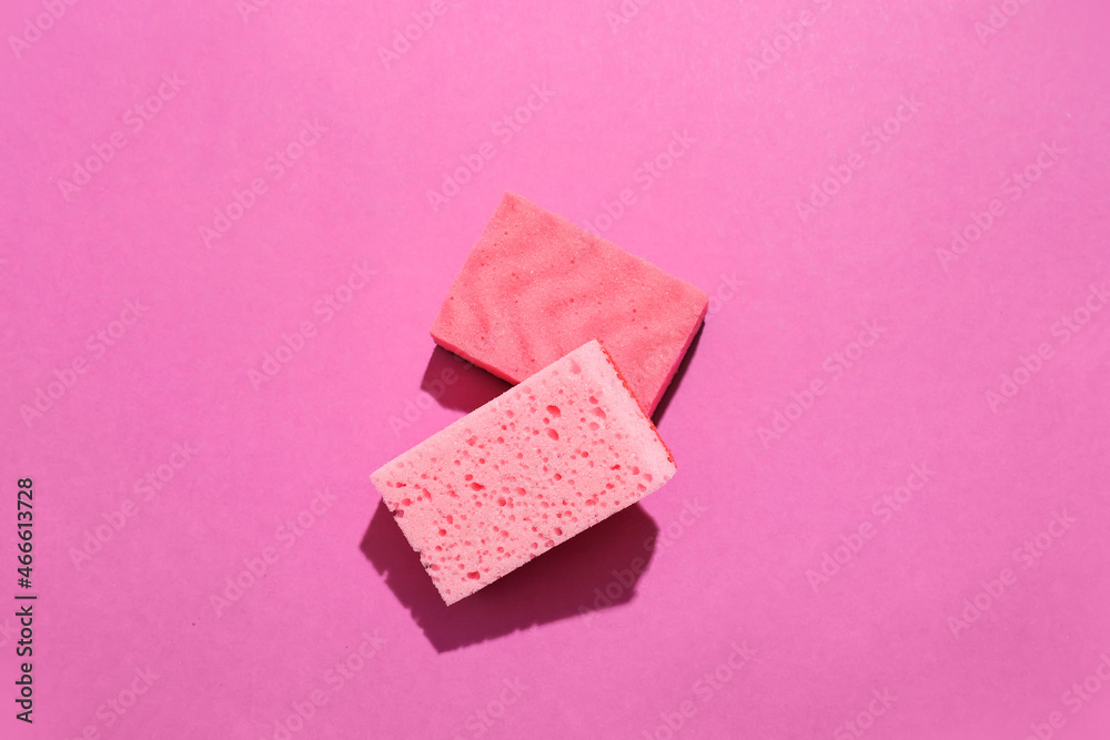 Pink cleaning sponges on color background