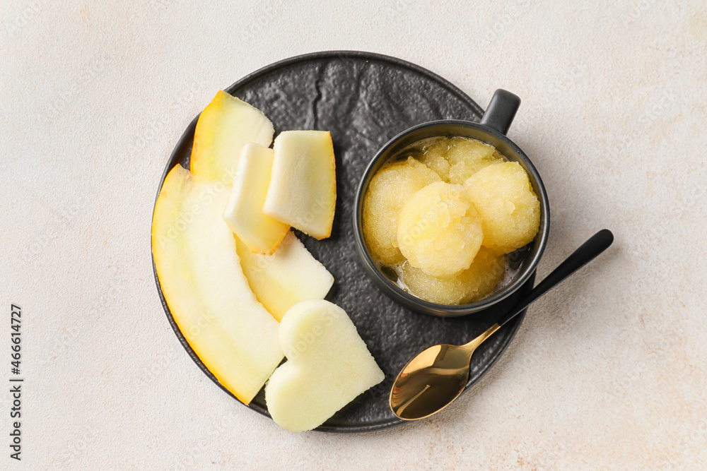 Cup with tasty sorbet and melon pieces on light background