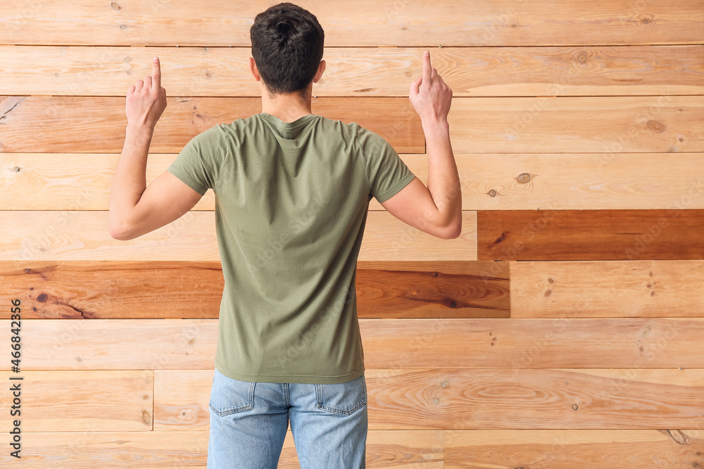 Handsome young man in stylish t-shirt on wooden background, back view