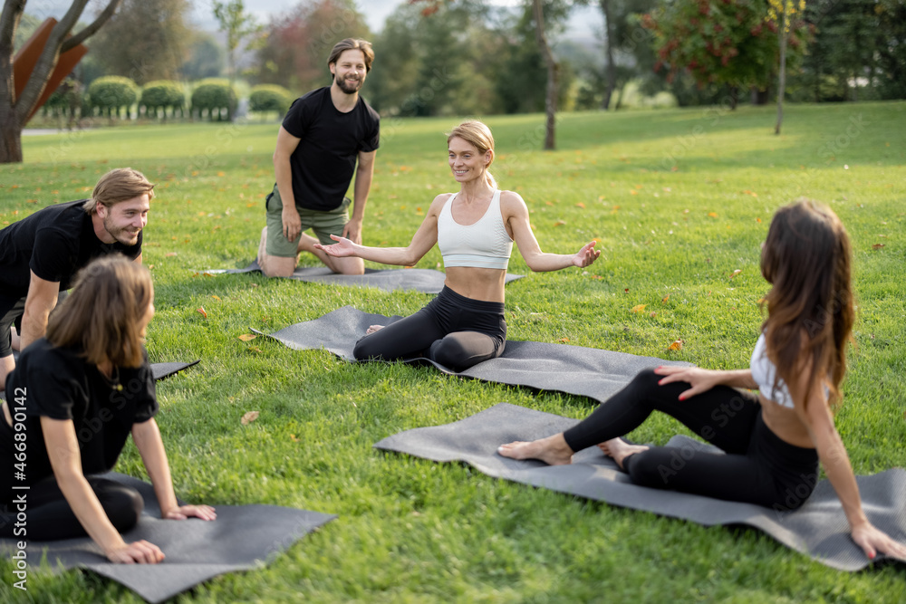 Group of european people resting on fitness mats and talking on green meadow. Concept of healthy lif