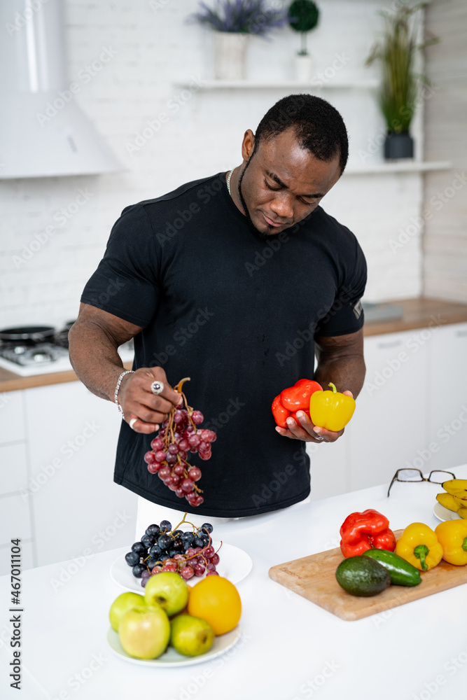 Handsome young man choosing freah healthy fruits. Attractive man cooking vegetarian fruit meal.