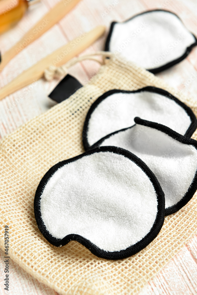 Reusable cotton pads and bag on light wooden background