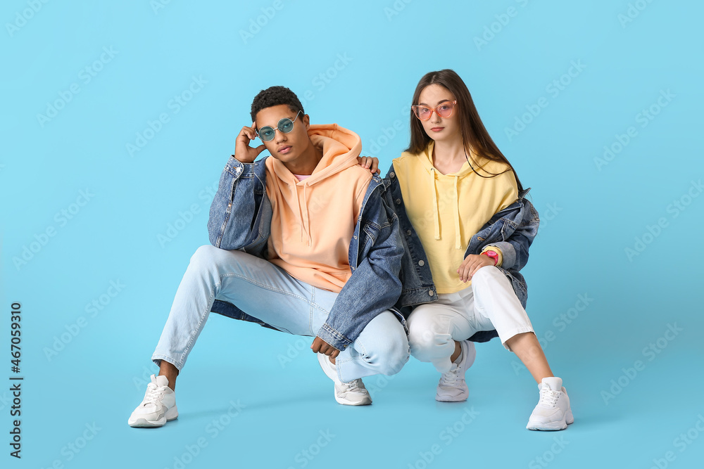 Stylish young couple in hoodies on blue background