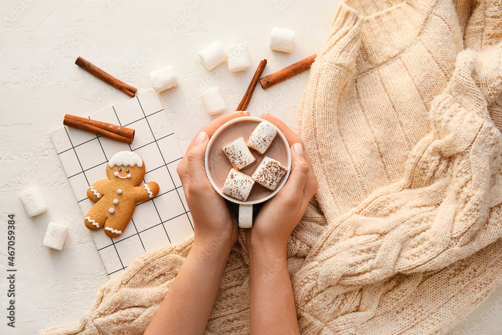 Woman holding cup of cacao with marshmallow, sweater, notebook, cookie and cinnamon on white backgro