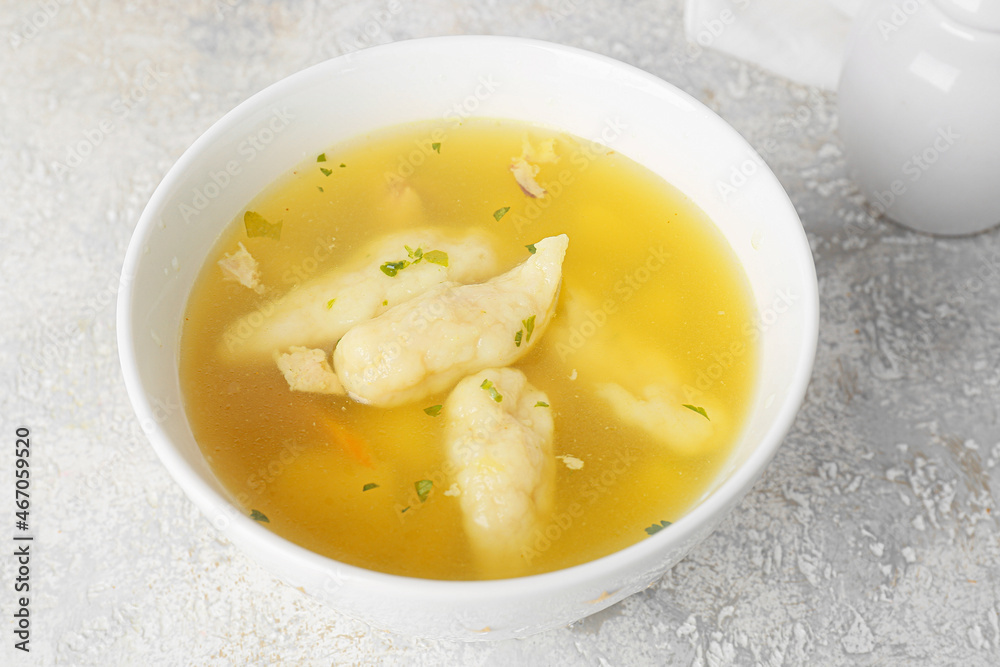 Bowl with delicious dumpling soup on light background