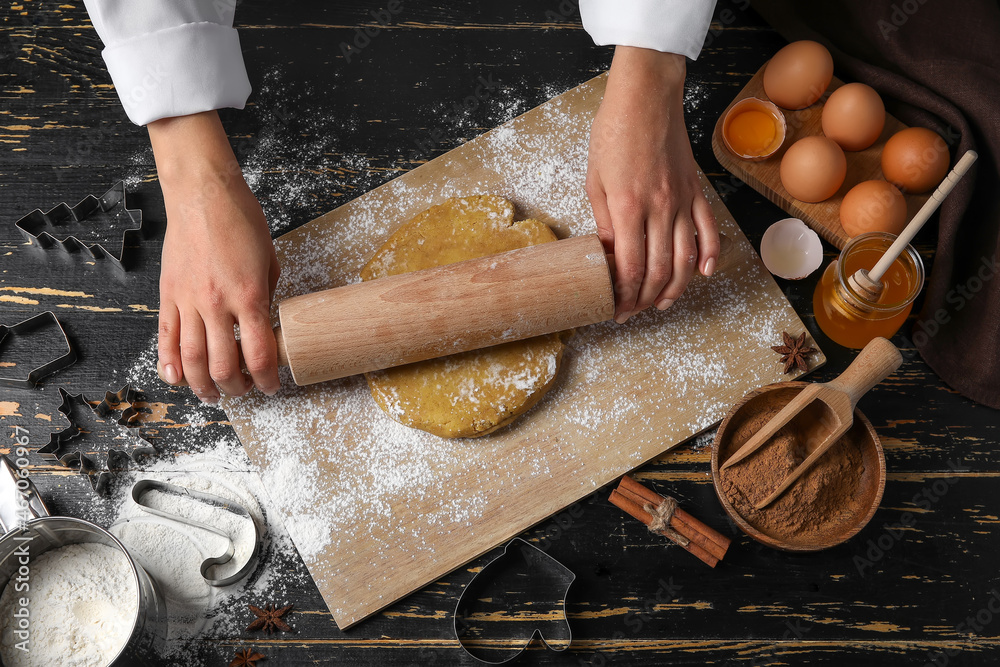 Confectioner rolling out gingerbread dough on table