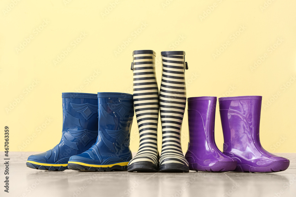 Different rubber boots on floor near color wall