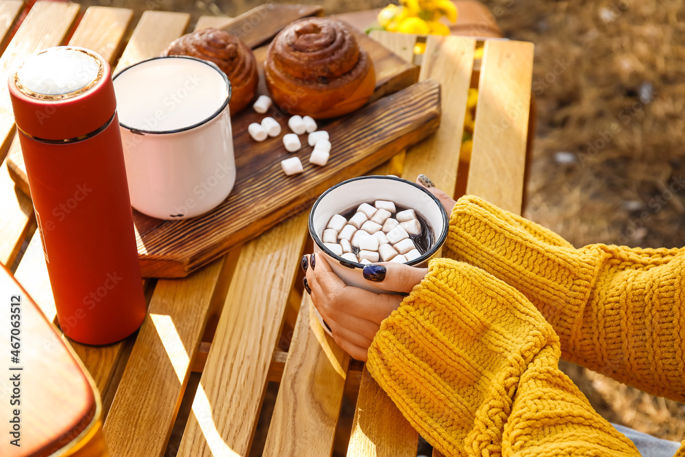 Young woman drinking hot chocolate on autumn day