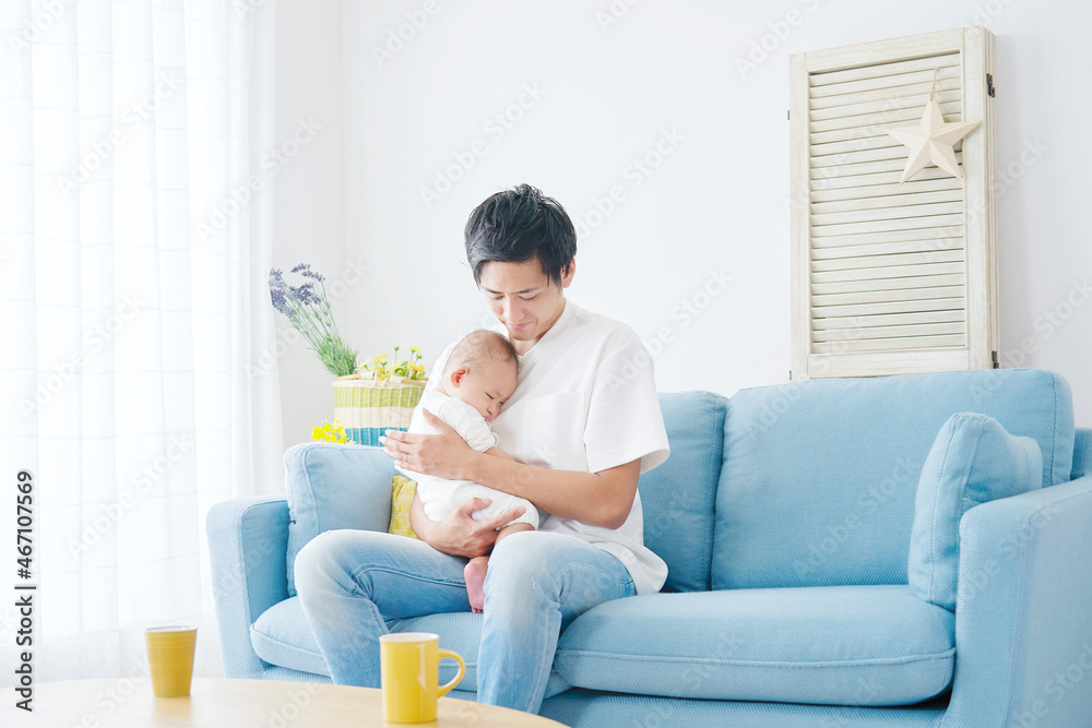 部屋で赤ちゃんを抱っこする父親