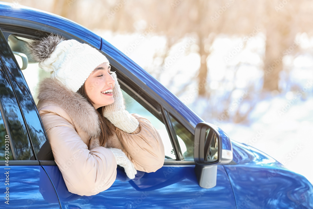 Young woman sitting in car on winter day