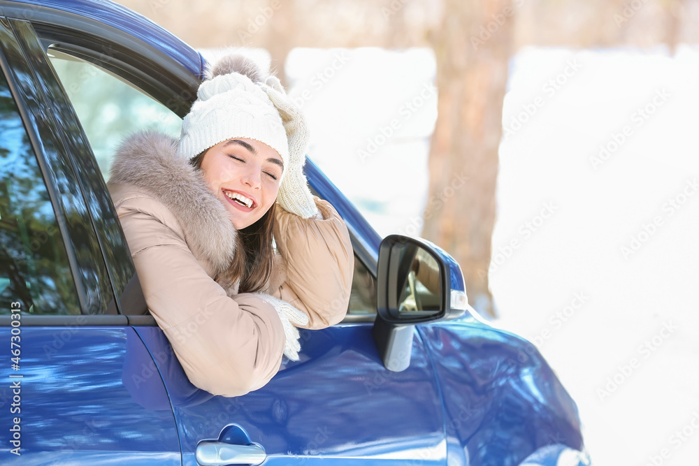 Young woman sitting in car on winter day