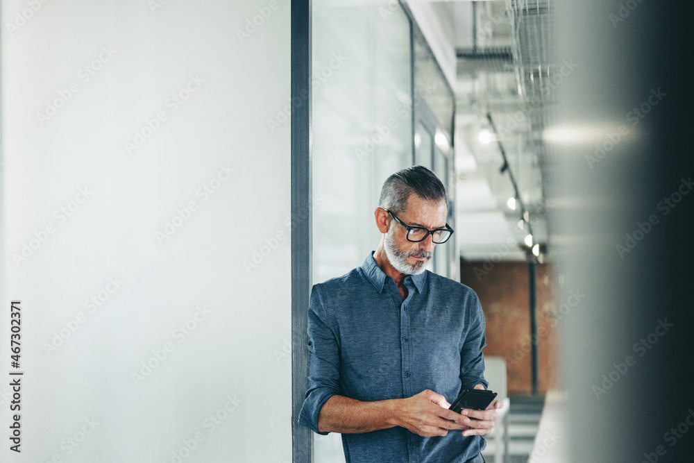 Experienced businessman using a smartphone in an office