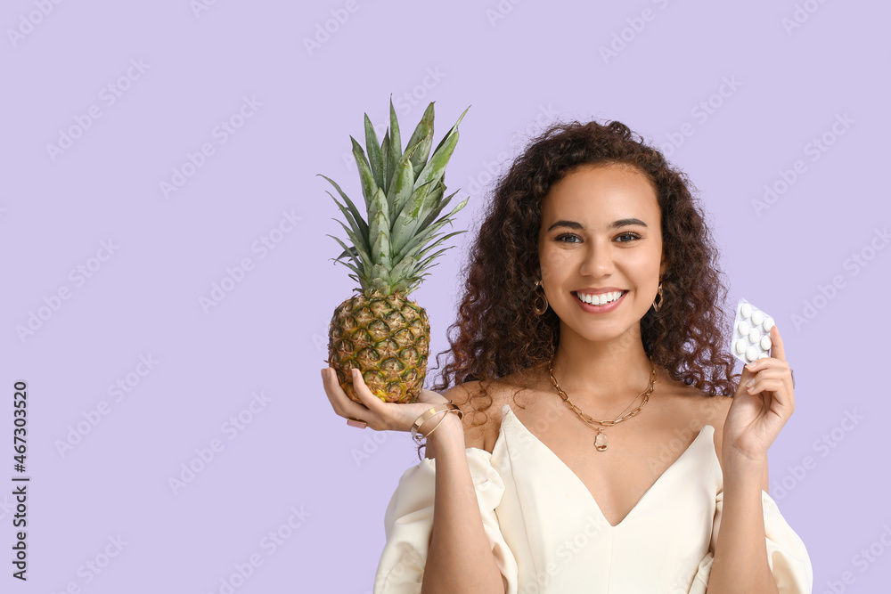 Happy African-American woman with chewing gum and pineapple on color background