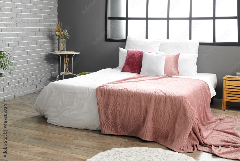 Interior of modern room with big comfortable bed and pink blanket