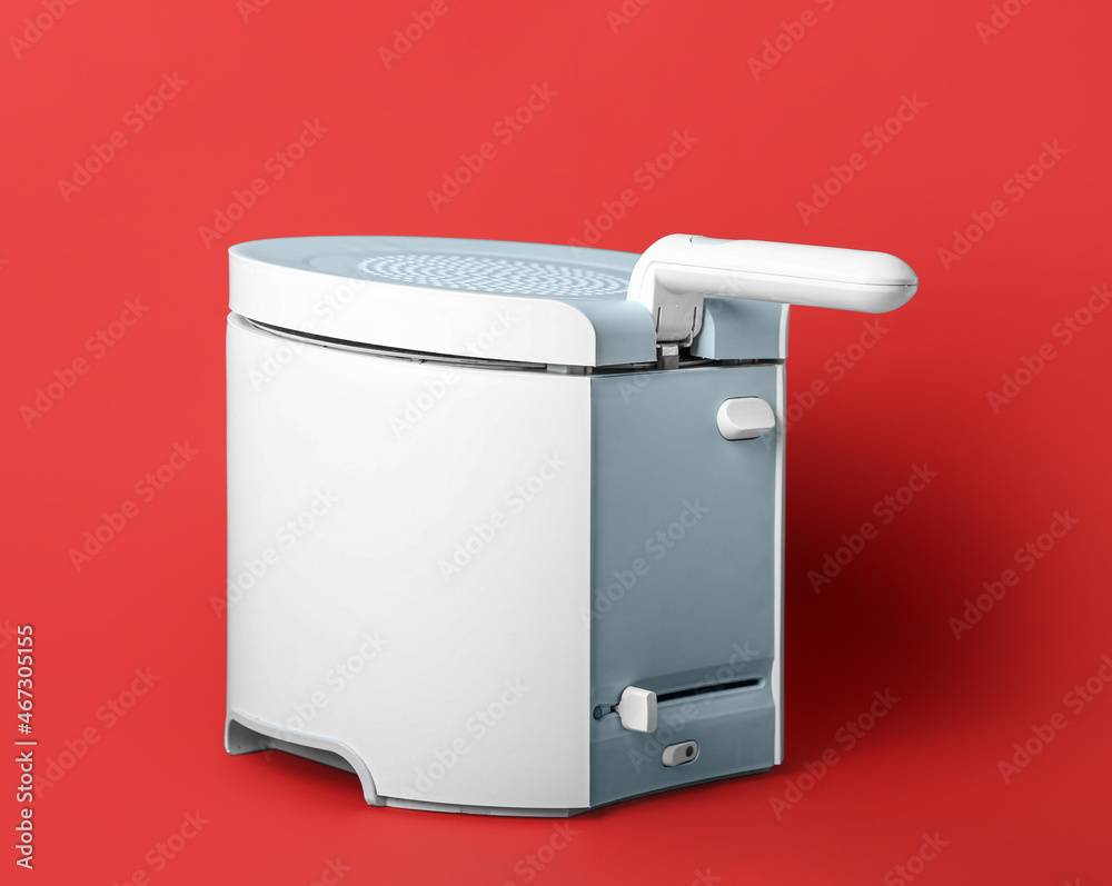 Modern deep fryer on color background