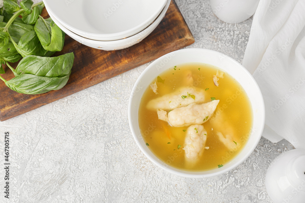 Bowl of delicious dumpling soup on light background